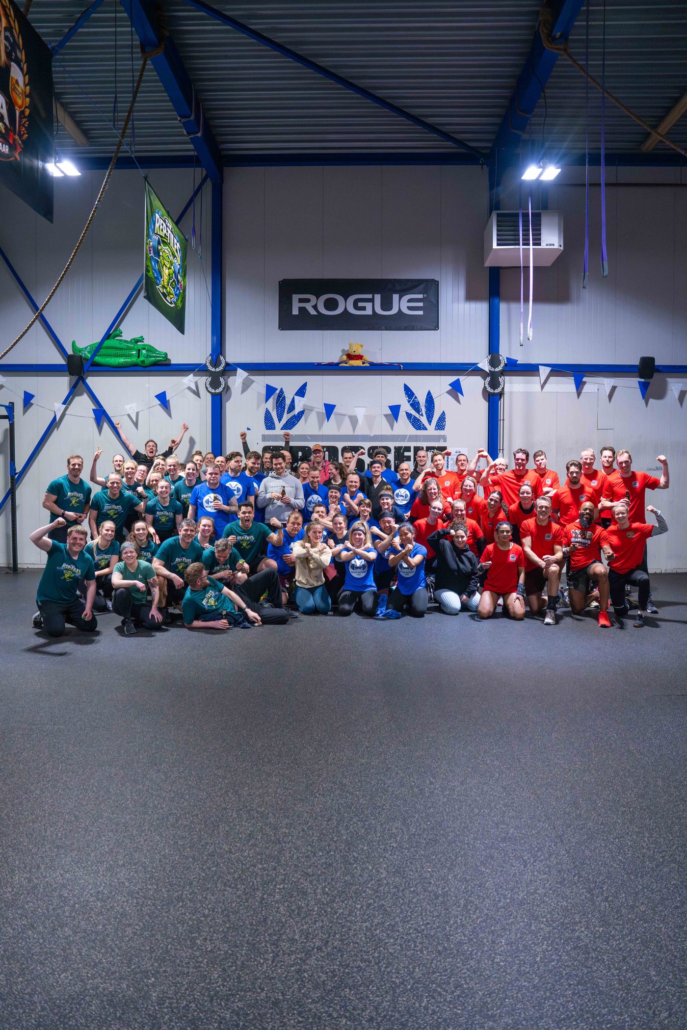 De drie teams van de CFA Open in groene, blauwe en rode shirts samen op de groepsfoto bij CrossFit Alkmaar