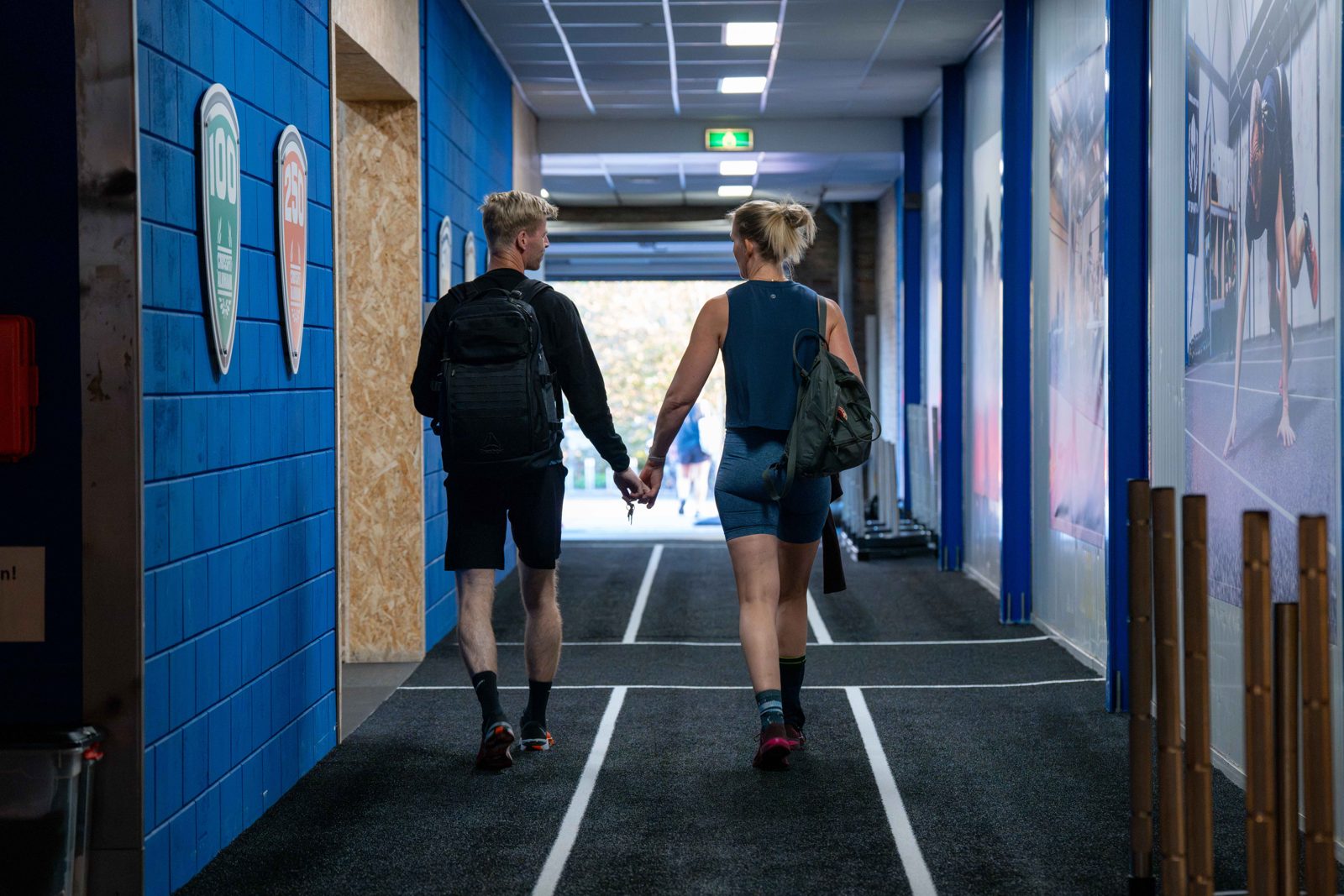 Twee leden lopen met een rugzak door de gang van CrossFit Alkmaar